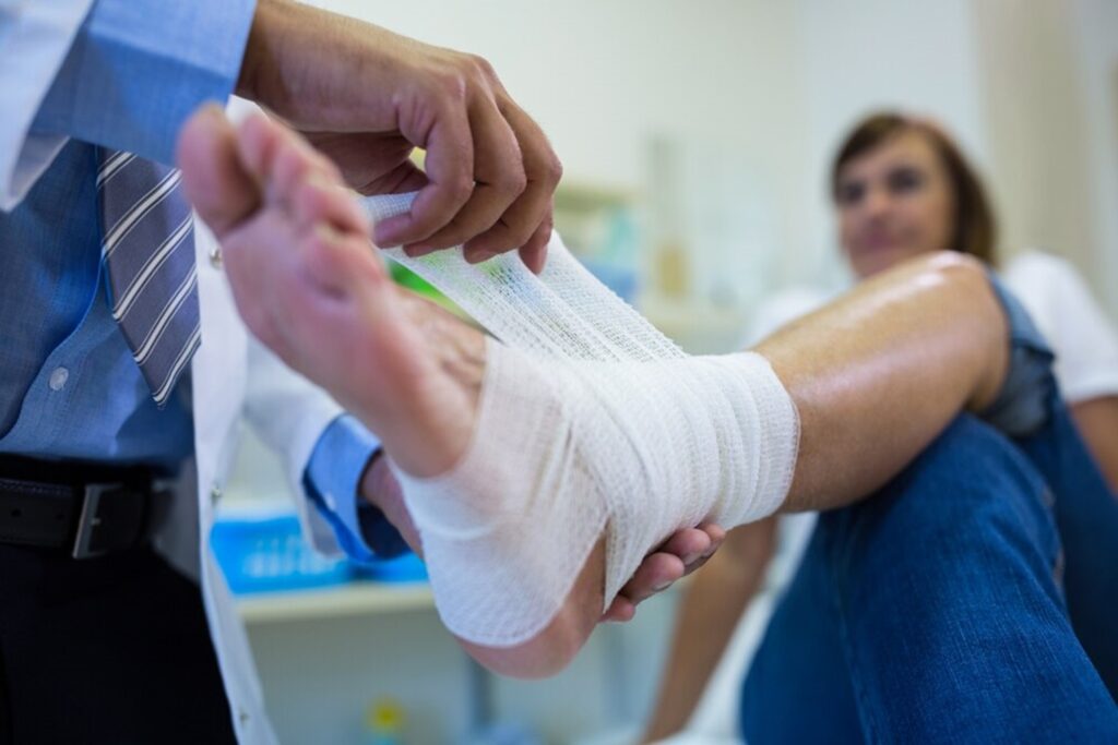 Qué es un esguince y cómo recuperarse: médico poniéndole una venda a un chico con esguince