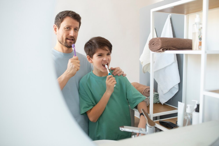 Como usar hilo dental: padre e hijo cepillándose los dientes cuidando su higiene bucal