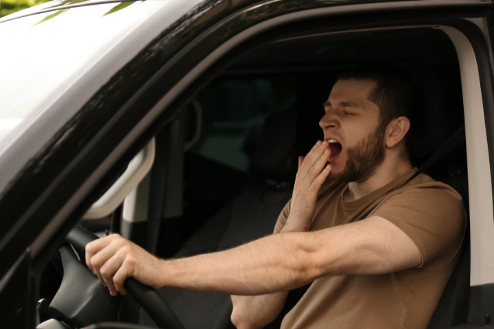 conducir con sueño: hombre bostezando mientras conduce